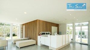 Un espace d’accueil moderne avec un mur d’accent en bois, un comptoir de réception et un coin salon équipé d’un banc.