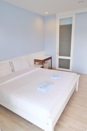 A bedroom with a large bed, a small table, and a wardrobe. - The Sea Condominium A22 (Sam Roi Yot)