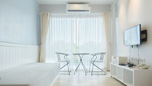 Une chambre d’hôtel moderne équipée d’un lit, d’une petite table avec deux chaises, d’un téléviseur fixé au mur et d’un bureau avec un téléphone et d’autres objets.