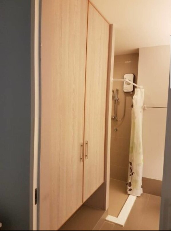 Un baño con armario de madera, ducha con cortina y un inodoro.
