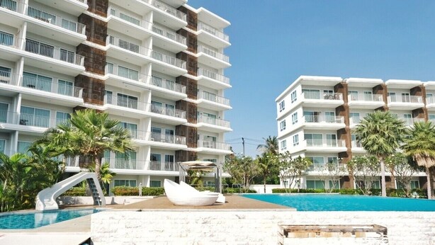Un hôtel doté de nombreux balcons, d’une piscine et de palmiers.