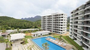 Un hôtel moderne doté d’une piscine centrale, de nombreux balcons et d’une végétation luxuriante en arrière-plan.