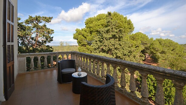 A balcony with wicker furniture and a view of a forest.