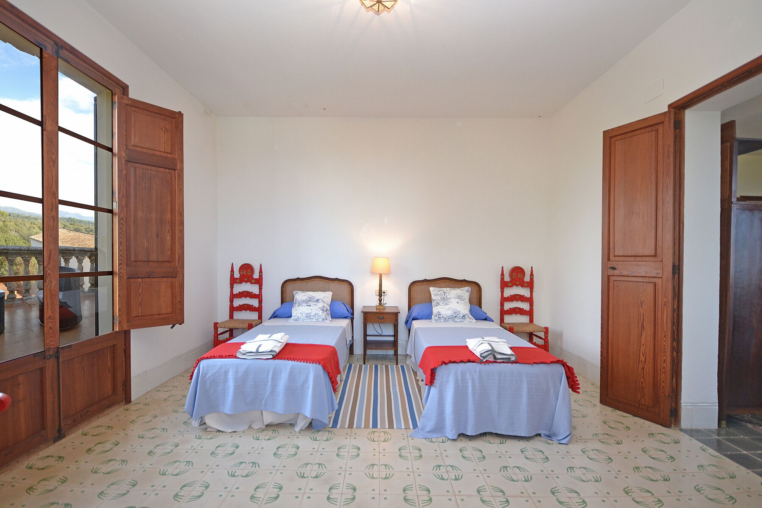A room with two beds, a window, and a door.
