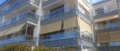 Un edificio residencial de varios pisos con balcones, barandillas y toldos.