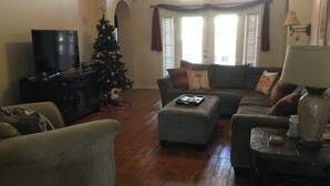 Un salon avec un sapin de Noël, un téléviseur et un canapé.