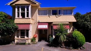 A two-story building with a sign for a backpacker hostel. - Rucksacker Backpacker Hostel (Christchurch)