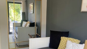 Une chambre à coucher avec un lit, un grand miroir, un radiateur et une vue sur un balcon extérieur.