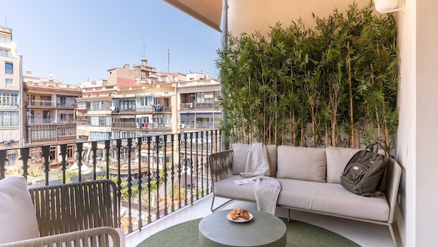 Un balcone con un divano, sedie, un tavolino e vista sugli edifici.