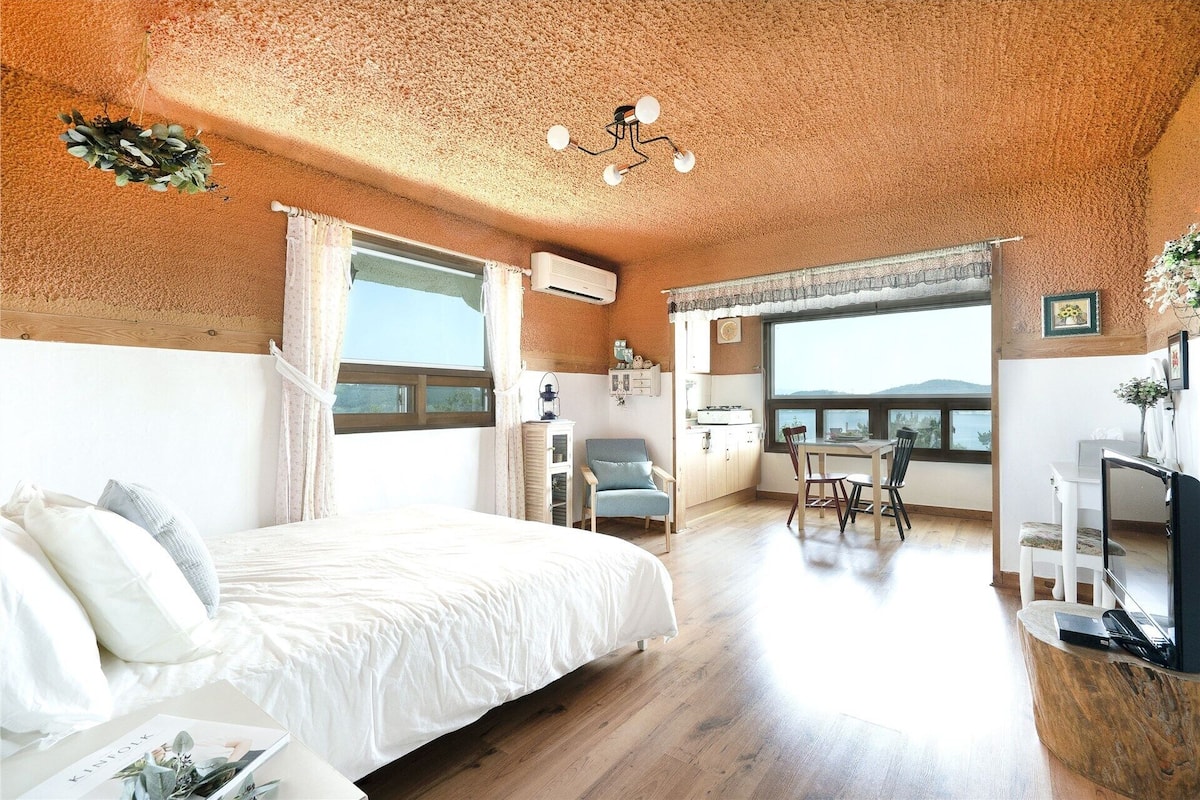 Un dormitorio con una cama grande, un escritorio y vista al mar.