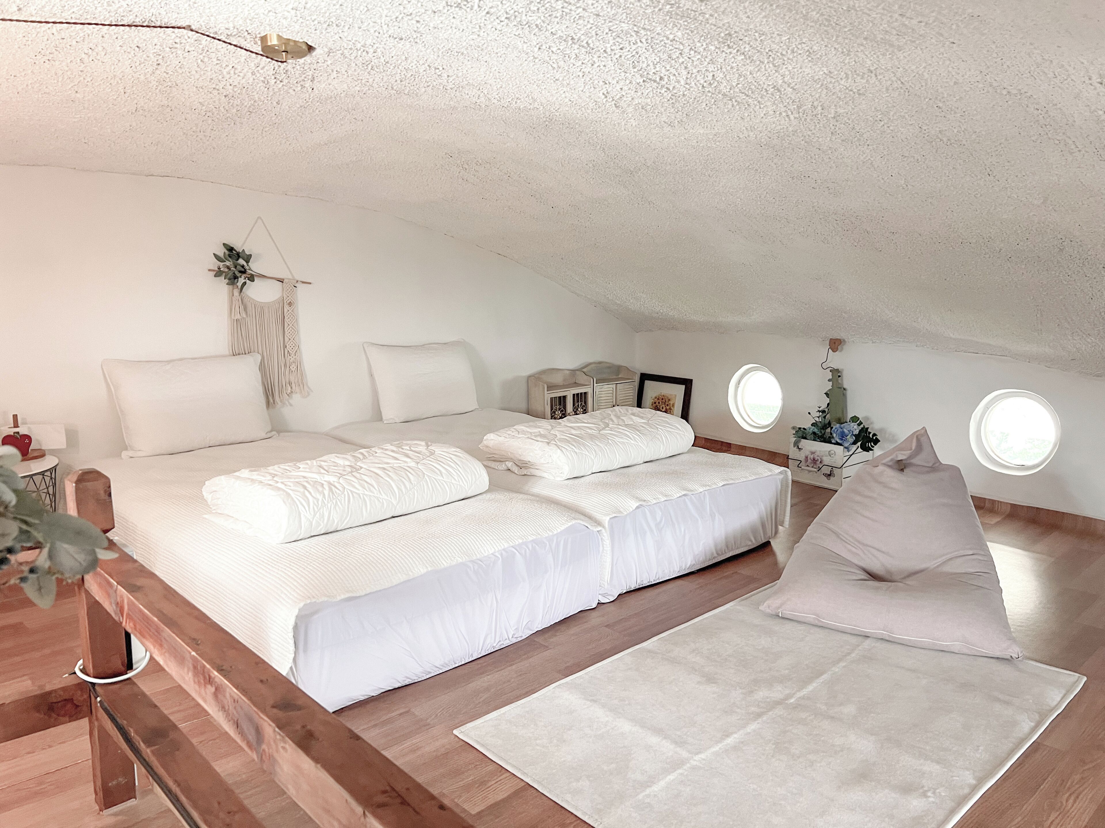 Un dormitorio abrigado en el ático con una cama grande, un banco de madera y una mesita.