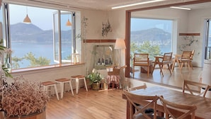 Spaziosa sala da pranzo con arredi in legno e ampie finestre che si affacciano sul mare e sulle colline.
