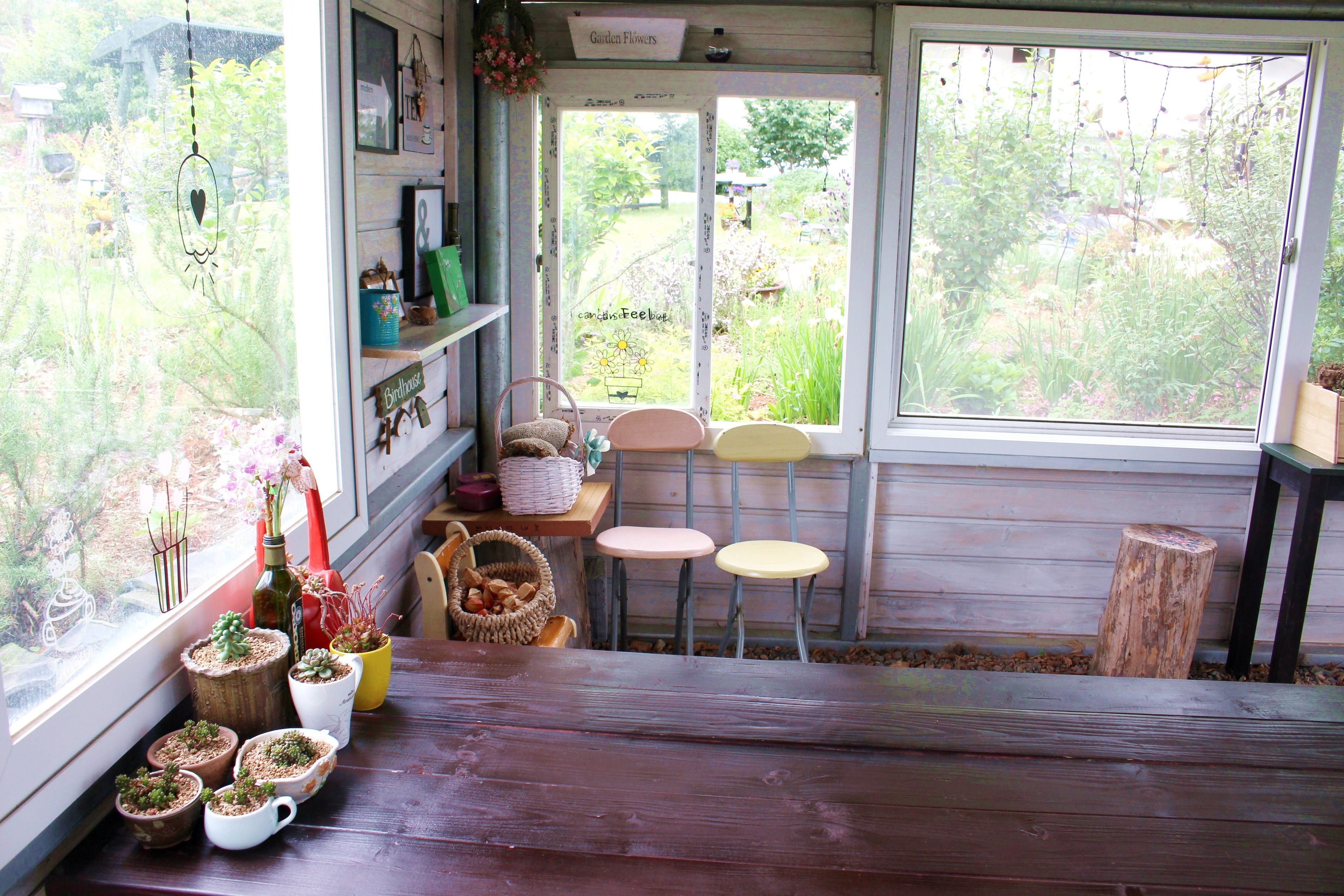 Una habitación acogedora con un banco de madera, una mesita con sillas y varias plantas en macetas.