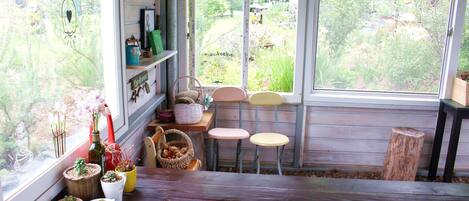 Una habitación acogedora con un banco de madera, una mesita con sillas y varias plantas en macetas.