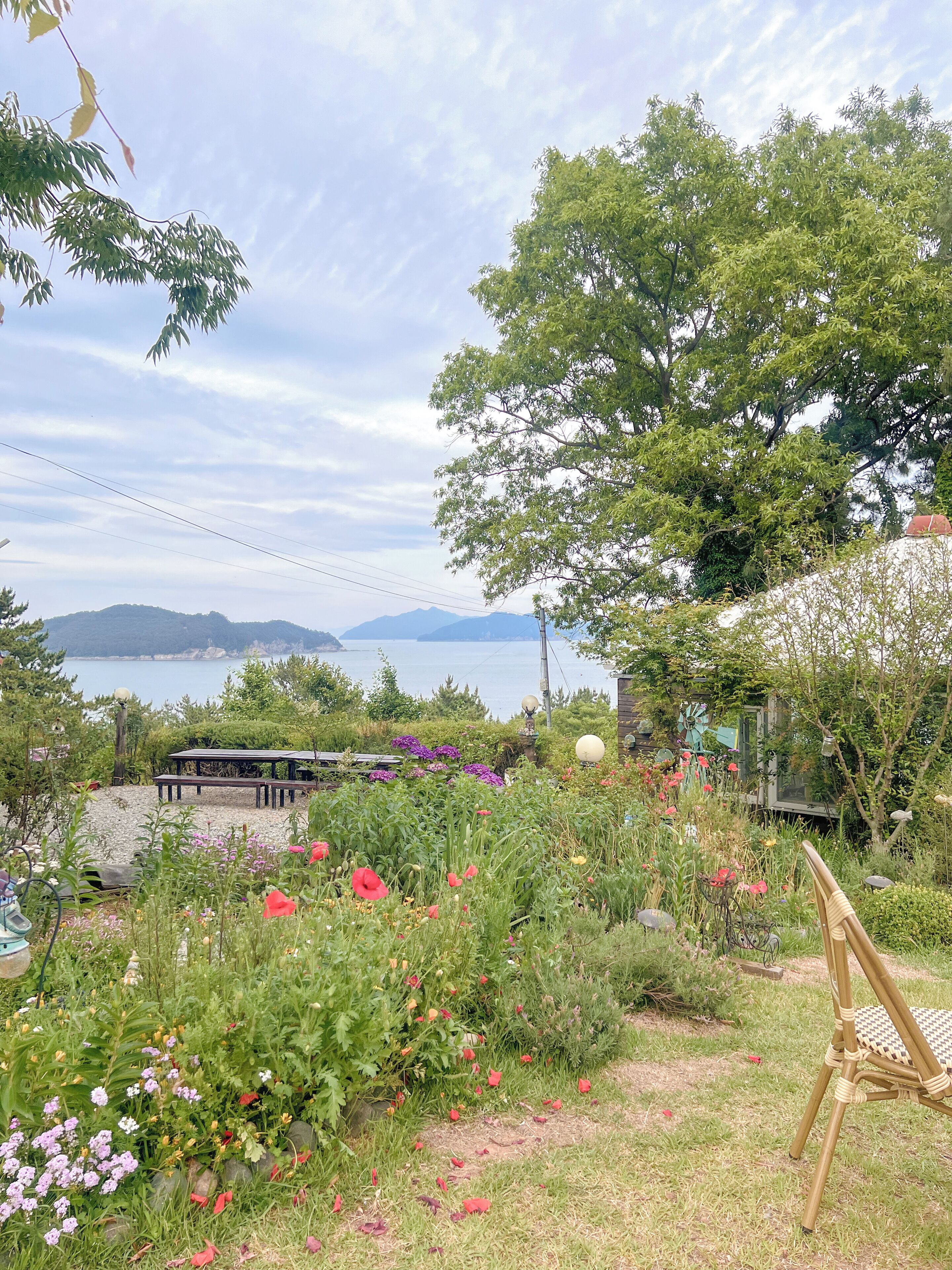 A garden with a bench, a chair, and a view of a lake and mountains.