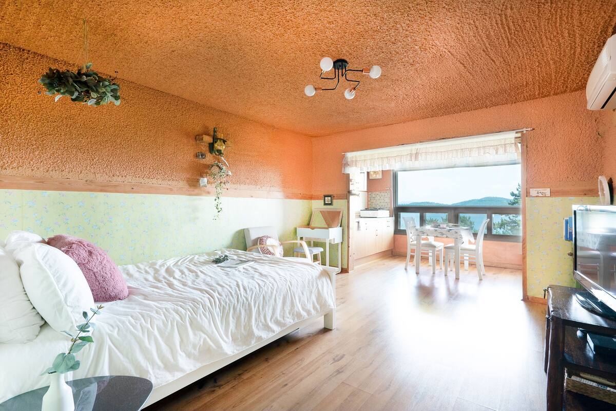 Un dormitorio con cama, escritorio, silla y balcón con vistas.