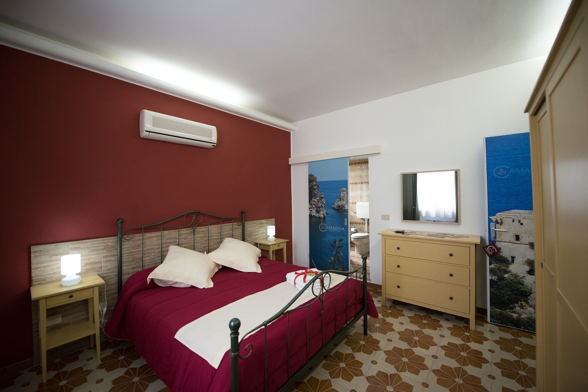 A bedroom with a bed, bedside tables, a dresser, and a wall-mounted air conditioner.