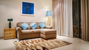 A modern living room with a sectional sofa, a side table, a floor lamp, and a large abstract painting on the wall. - The Ocean Suites - A504 Tower A (Da Nang)