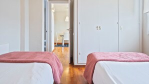 Ett hotellrum med två sängar, en garderob och ett badrum som syns genom en öppen dörr.
