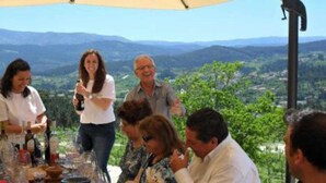 Un groupe de personnes s’est réuni autour d’une table où étaient posées des bouteilles de vin, dans un cadre offrant une vue magnifique sur les montagnes.