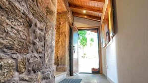 Un escalier en pierre mène à une porte en bois, et une grille métallique se trouve en bas.