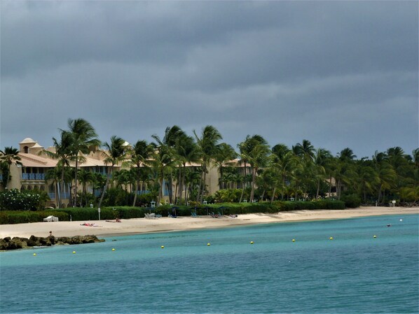 Ein Hotel an der Küste mit Strand, Palmen und klarem, blauem Wasser.