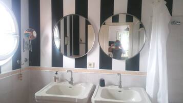 Un baño con dos lavamanos, un espejo y una pared a rayas.