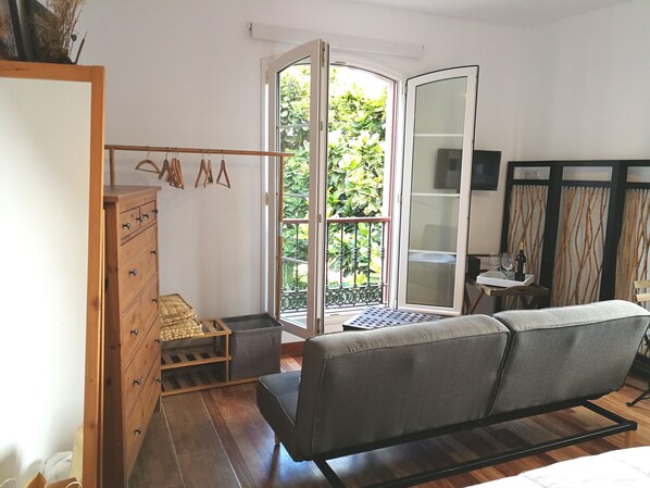A room with a sofa, wooden dresser, and a sliding glass door leading to a balcony with greenery. - SWEET DREAMS Beautiful Apartment. Light, Comfort, Tranquility (Sta Brígida)