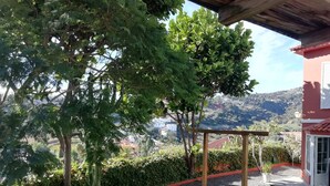 A covered outdoor area with a wooden pergola, a well-maintained lawn, and a view of a hillside with buildings in the distance. - SWEET DREAMS Beautiful Apartment. Light, Comfort, Tranquility (Sta Brígida)