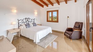 Une chambre à coucher comprenant un lit, une table de chevet, une lampe, une chaise et une fenêtre donnant sur l’extérieur.