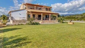Une maison en pierre à deux étages, dotée d’un balcon, d’une façade en pierre et d’une pelouse bien entretenue.