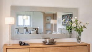 Une commode en bois avec un miroir, une lampe et un vase rempli de fleurs.
