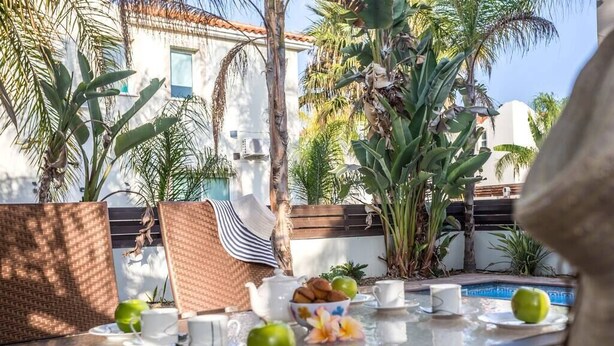 Ein Frühstückstisch mit Blick auf einen Pool und Palmen.