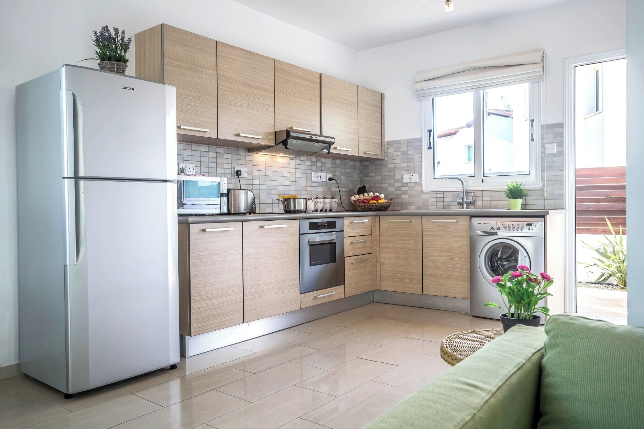 A modern kitchen with a refrigerator, oven, microwave, and washing machine.