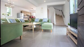 Ein modernes Wohnzimmer mit einem grünen Sofagarnitur, einem Holztisch und einem Flachbildfernseher auf einem Holzboden.