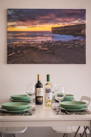A dining table set with green plates, two wine bottles, and wine glasses.