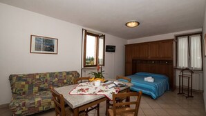 Une pièce de taille modeste comprenant un lit, une table à manger avec des chaises, un canapé et un petit coin cuisine.