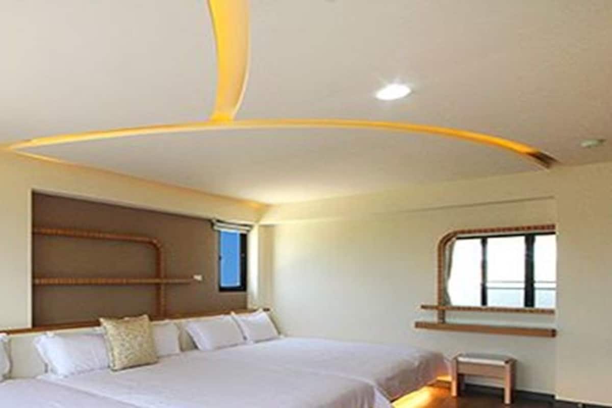 A hotel room with a large bed, a small bedside table, and a window with a view.
