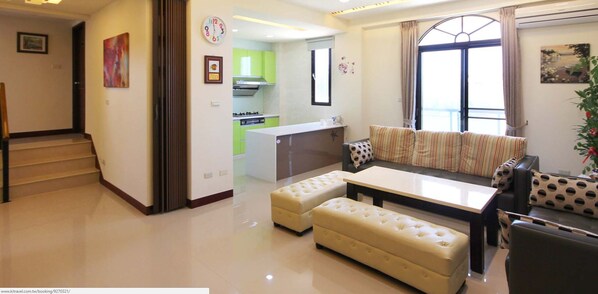 A modern living room with a sofa set, a dining table, and a kitchen in the background. - Sea Sky Coast Homestay (Magong)