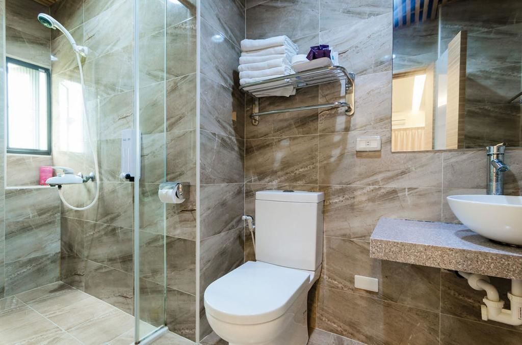A modern bathroom with a glass shower enclosure, a toilet, and a sink with a marble countertop.