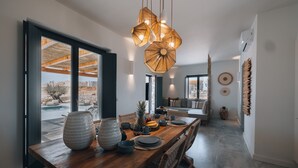 Un espace repas moderne avec une table en bois, des chaises en osier et un luminaire suspendu.