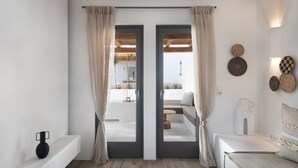 A modern bedroom with a bed, a bedside table, a mirror, and a view of an outdoor balcony.