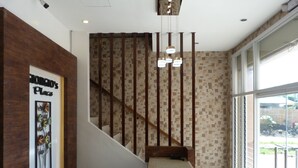 A staircase with a wooden handrail and a wall with a patterned tile design. - Giorgio's Place (Polomolok)