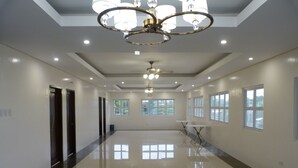 A spacious, well-lit hallway with a polished floor, large windows, and a modern chandelier. - Giorgio's Place (Polomolok)