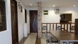 A dining area with a long table and multiple chairs, a pillar, and a door with a number. - Giorgio's Place (Polomolok)