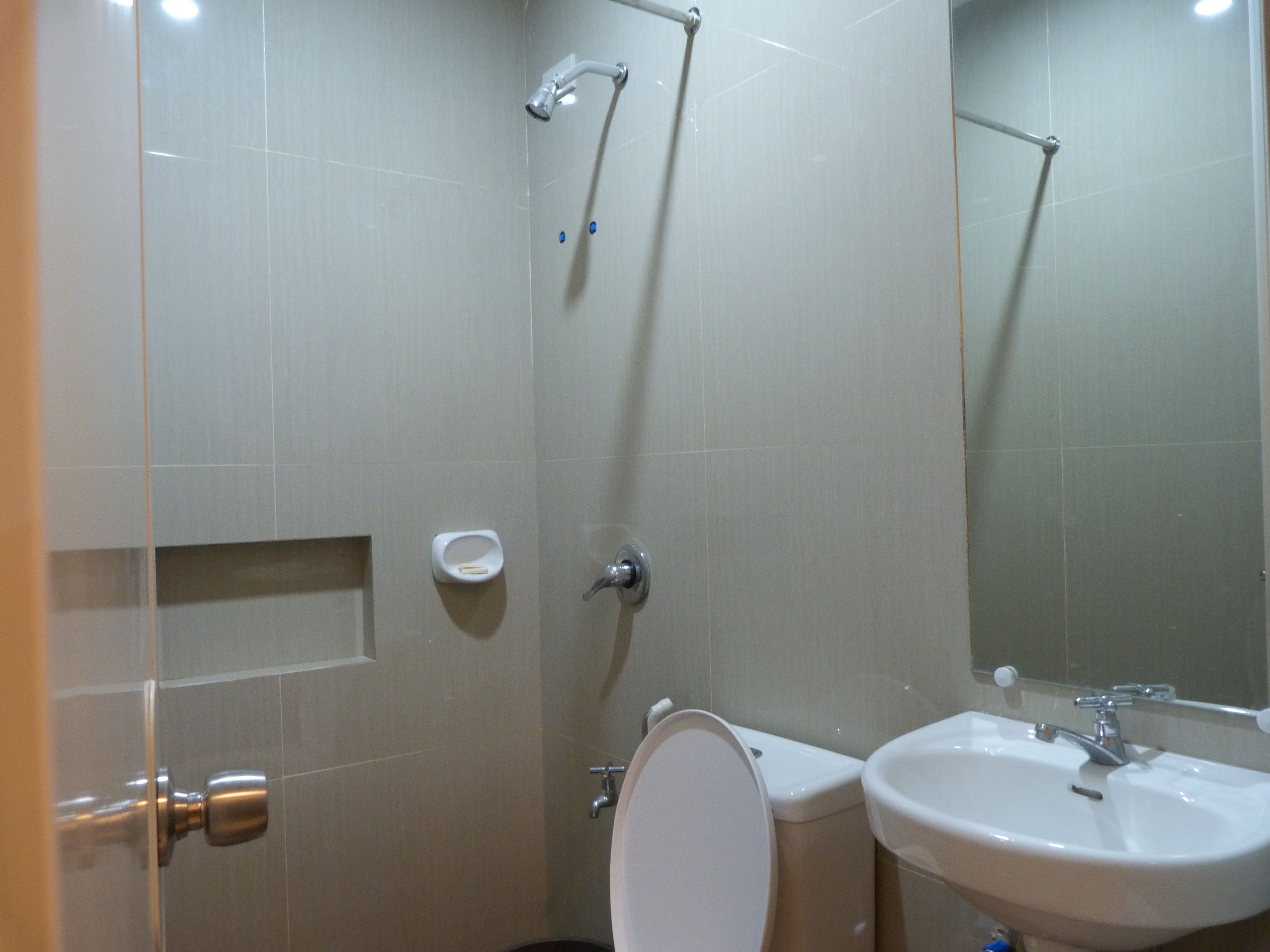 A bathroom with a toilet, sink, and shower.
