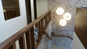 A staircase with wooden railings, a tiled wall, and a wall-mounted light fixture. - Giorgio's Place (Polomolok)