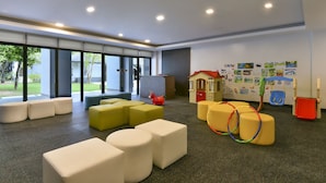 Un espacio interior moderno con zonas de estar, una casita de juegos y obras de arte en las paredes.