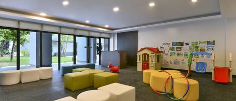 A modern indoor space with seating areas, a playhouse, and artwork on the walls.