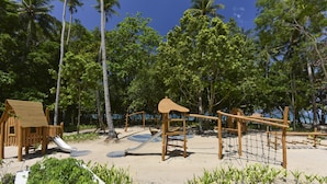 Un parque infantil con un tobogán, estructuras para escalar y una casita de madera.